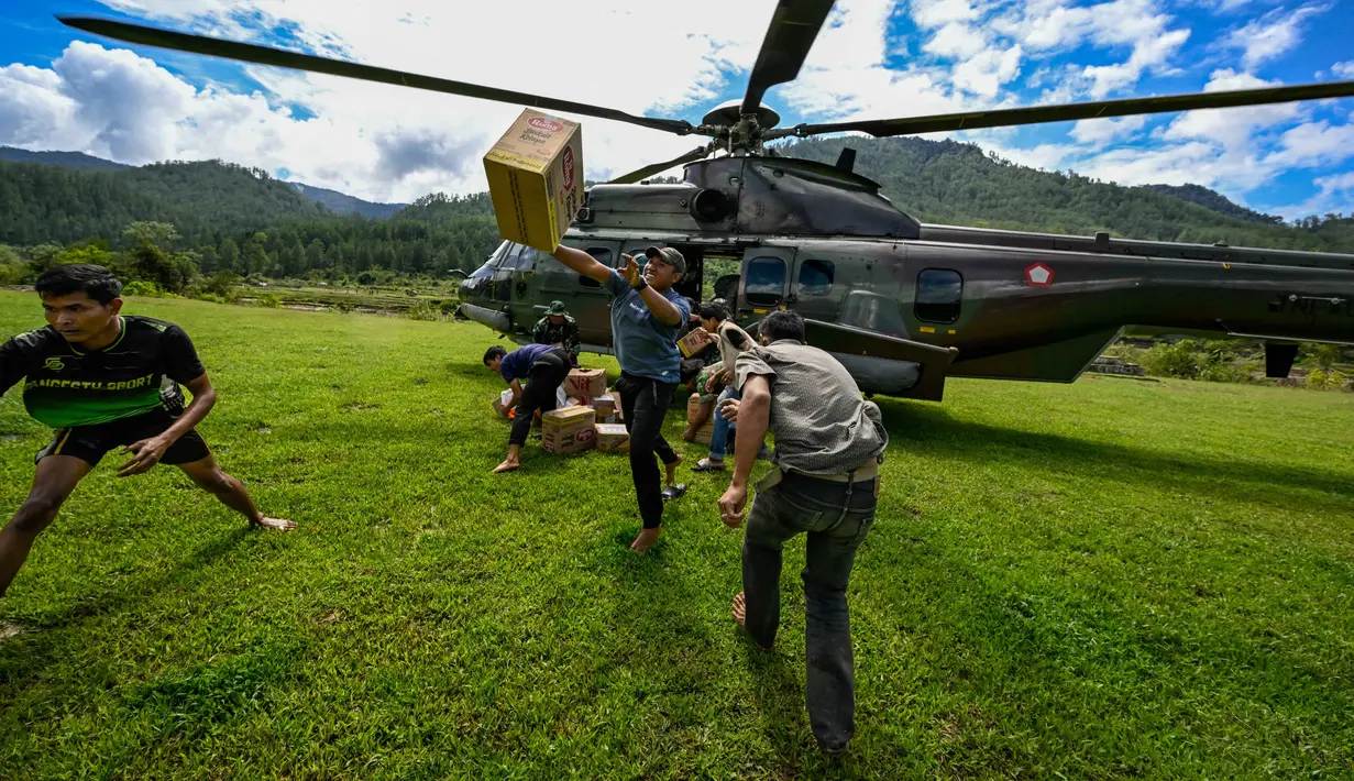 Warga membawa bantuan yang didistribusikan oleh personel TNI AU di wilayah terdampak banjir di Kabupaten Bener Meriah, Provinsi Aceh, pada Kamis 4 Desember 2025. Pendistribusian bantuan logistik bagi masyarakat terdampak banjir bandang di beberapa kabupaten di Aceh, terus dilakukan. (CHAIDEER MAHYUDDIN/AFP)