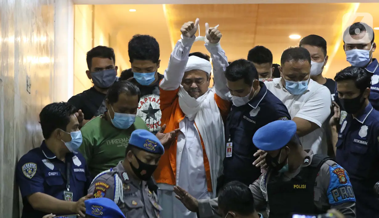 M Rizieq Shihab (tengah) digiring petugas saat meninggalkan gedung Ditreskrimum Polda Metro Jaya, Jakarta, Minggu dini hari (13/12/2020). Rizieq Shihab ditahan setelah menjalani pemeriksaan sebagai tersangka penghasutan dan kerumunan di tengah pandemi COVID-19. (Liputan6.com/Helmi Fithriansyah)