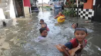 Hujan yang mengguyur Jakarta sejak Minggu (8/2) lalu, membuat Waduk Ria Rio meluap. Para bocah ini asyik bermain saat bajir melanda kawasan rumah mereka di Pendongkelan, Jakarta, Selasa (10/2/2015). (Liputan6.com/Herman Zakharia)