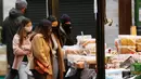 Pembeli makanan mengenakan masker saat berbelanja di Borough Market di London selatan selama penguncian nasional (lockdown) ketiga Inggris, Selasa (12/1/2021). Borough Market menjadi tempat pertama yang mewajibkan pemakaian masker di luar ruangan. (AP Photo/Alastair Grant)