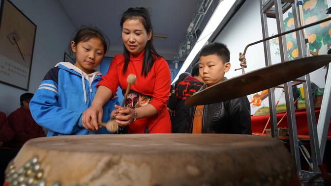 Seorang seniman wayang kulit mengajari siswa cara bermain gendang di Sekolah Dasar Xiyoucun di Kota Shahe, Provinsi Hebei, China utara, pada 24 November 2020. (Xinhua/Fan Shihui)