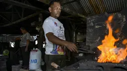 Seorang pandai besi memanaskan baja untuk membuat pisau di bengkel tradisional di Darul Imarah, provinsi Aceh (4/11/2019). Lebih 70 persen warga di desa ini memiliki bekerja sebagai pengrajin pandai besi. (AFP Photo/Chaideer Mahyuddin)