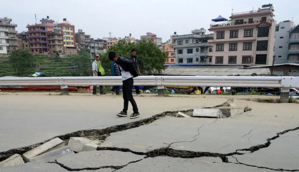 Sejumlah warga Kathmandu melihat jalan yang rusak akibat gempa , Minggu (26/4/2015). Gempa berkekuatan 7,8 Skala Richter dikabarkan telah menelan korban sekitar 2000 jiwa. (AFP Photo/Prakash Mathema)