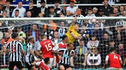 Penjaga gawang Arsenal, Aaron Ramsdale (tengah atas), berhasil menghalau bola serangan dari pemain Newcastle United dalam laga pekan ke-35 Premier League 2022/2023 yang berlangsung di St James Park, Minggu (7/5/2023). (AFP/Lindsey Parnaby)