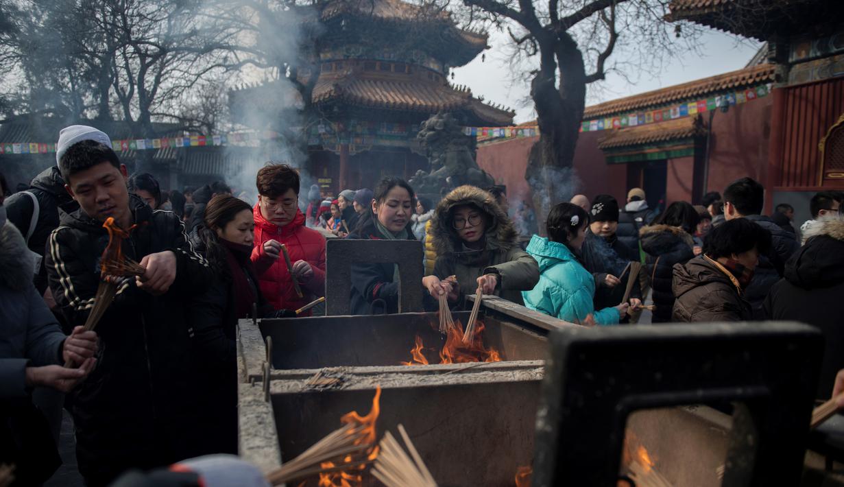 Sejumlah warga membakar dupa untuk berdoa keberuntungan pada hari kelima Tahun Baru Imlek di Yonghegong, atau Kuil Lama di Beijing (9/2). Warga China merayakan Tahun Babi tersebut dengan doa, pesta keluarga, dan belanja. (AFP Photo/Nicolas Asfouri)