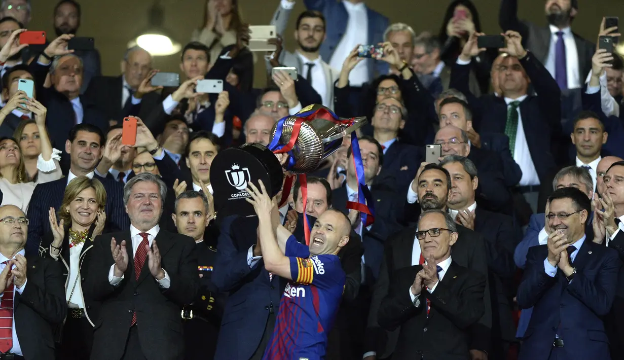 Kapten Barcelona, Andres Iniesta, mengangkat trofi usai menjuarai Copa del Rey setelah mengalahkan Sevilla di stadion Wanda Metropolitano, Madrid, Minggu (22/4/2018). Barcelona menang 5-0 atas Sevilla. (AFP/Cristina Quicler)