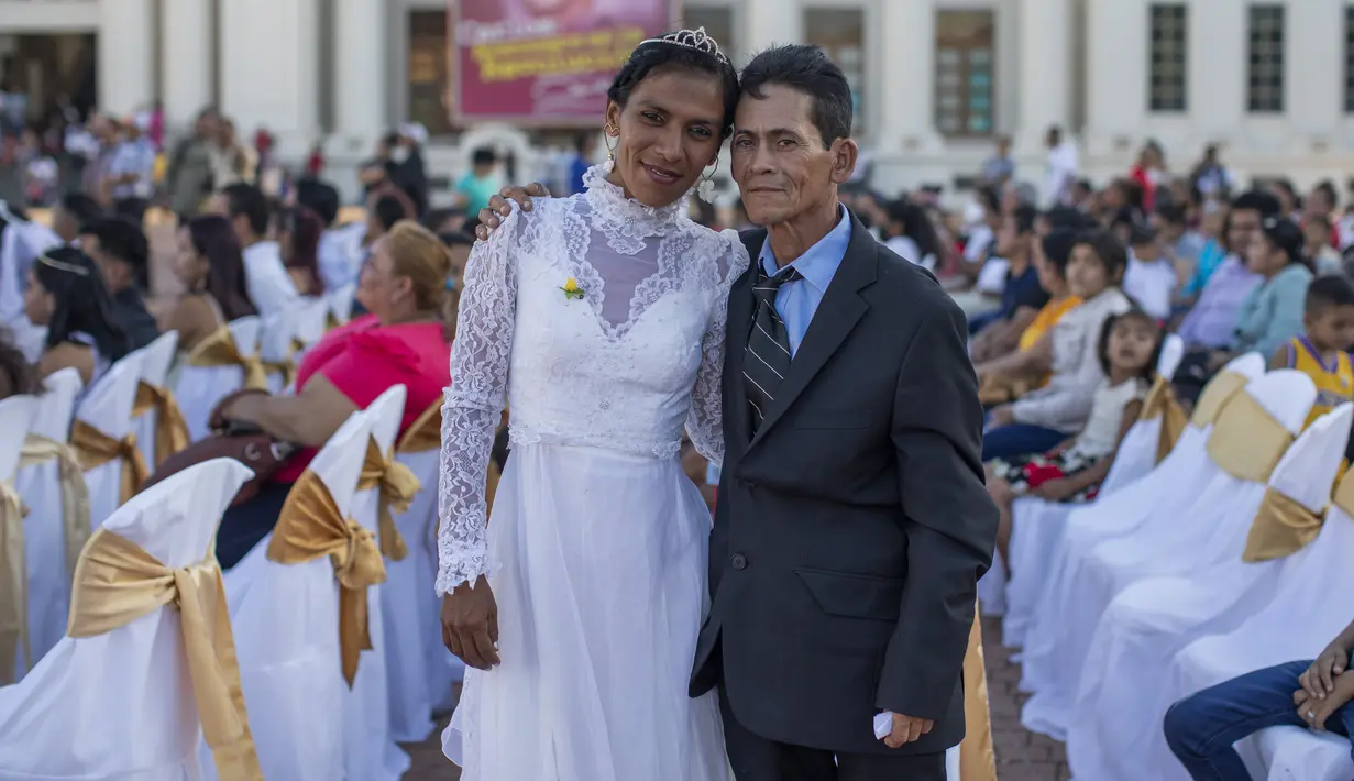 Pasangan suami istri berfoto usai mengikuti pernikahan massal di Managua, Nikaragua, Selasa  (14/2/2023). Acara tersebut diselenggarakan oleh stasiun radio Sandinista "La Nueva Radio Ya", dan sekitar 263 pasangan menikah di Lapangan Revolusi. (AP Photo/Inti Ocon)