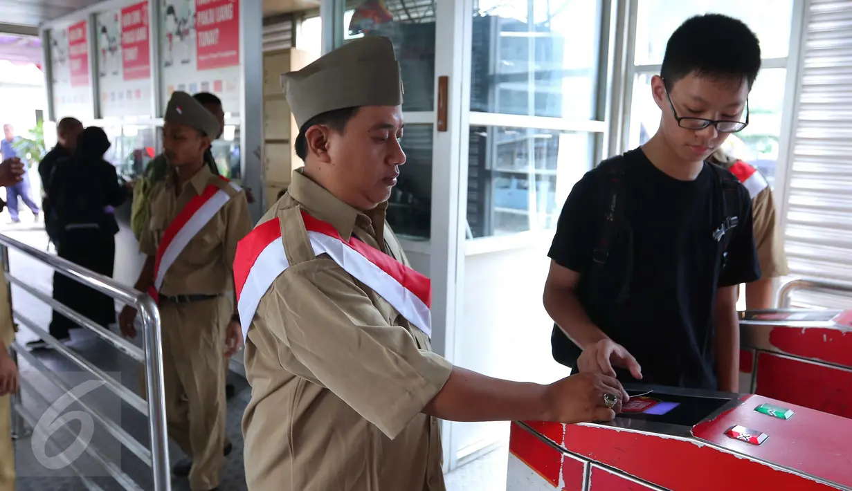 Petugas membantu penumpang untuk memasuki Trans Jakarta, Selasa (16/8). Petugas mengenakan pakaian tentara perjuangan tempo dulu untuk menyambut para penumpang. (Liputan6.com/Angga Yuniar)
