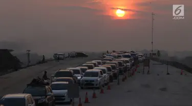 Kendaraan melintas saat matahari terbenam untuk keluar dari ruas Tol Batang-Semarang menuju jalur Pantura Batang-Kendal di Kali Kuto, Gringsing, Batang, Jawa Tengah, Senin (11/6). (Liputan6.com/Arya Manggala)