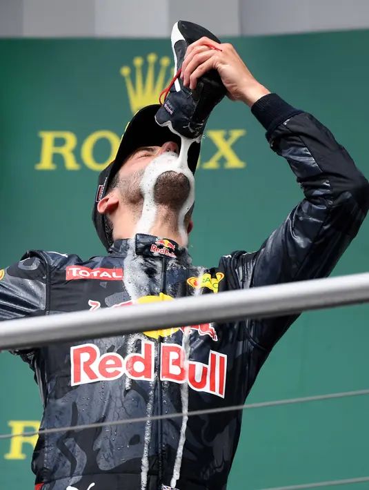 Selebrasi konyol, pembalap Red Bull Daniel Ricciardo saat merayakan keberhasilannya naik podium pada Grand Prix Formula 1 Jerman, Minggu (31/7). Ricciardo yang menjadi juara kedua meminum sampanye menggunakan sepatunya. (Patrik STOLLARZ / AFP)