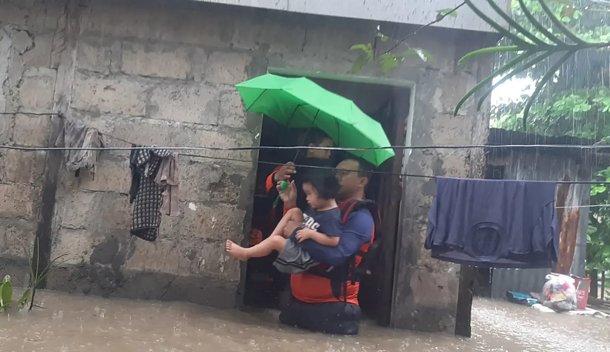 Para penyelamat mengevakuasi seorang anak dari daerah banjir di Kota Ozamiz, Misamis Occidental, Filipina (25/12/2022). Dua orang tewas dan hampir 46.000 lainnya meninggalkan rumah mereka saat banjir pada libur Hari Natal. (Handout / Philippine Coast Guard (PCG) / AFP)