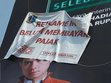 Sebuah reklame bergambar Dude Harlino tertutup spanduk di Kawasan Kebayoran Lama, Jakarta, Kamis (23/2). Reklame tersebut terkena razia oleh Satpol PP dan Dinas BP2T karena belum membayar pajak. (Liputan6.com/Gempur M Surya)