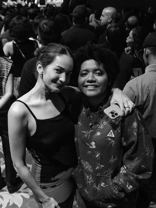 Foto hitam-putih menunjukkan kedekatan Enzy Storia dengan sang adik. Menonton konser bersama, Enzy Storia memilih mengenakan tank top hitam, sedangkan sang adik mengenakan hoodie bermotif floral. Foto: Instagram.