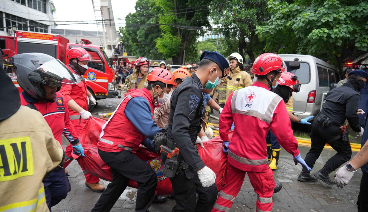 Petugas terus melakukan penyisiran ke seluruh bagian gedung hingga lantai enam. Tampak dalam foto, personel dari Dinas Penanggulangan Kebakaran dan Penyelamatan dibantu tim dari Brimob Polri mengevakuasi jenazah korban kebakaran di Jakarta, Selasa 9 Desember 2025. (AP Photo/Dita Alangkara)