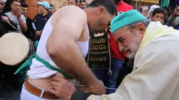 Warga muslim Sufi menusukkan benda tajam ke perut salah satu peserta saat perayaan Maulid Nabi Muhammad SAW di Sidon, Lebanon (30/11). Tradisi yang mirip debus ini selalu digelar setiap tahunnya. (AFP Photo/Mahmoud Zayyat)