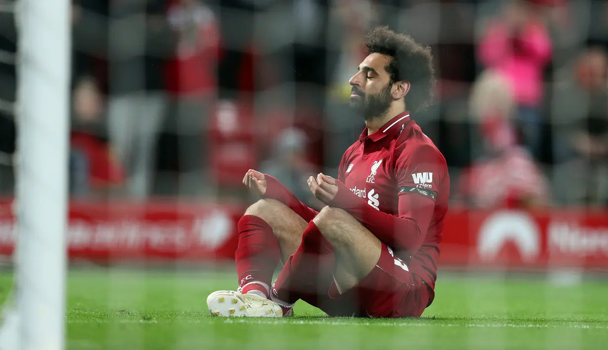 Winger Liverpool, Mohamed Salah duduk di depan gawang setelah mencetak gol ke gawang Huddersfield Town dalam laga lanjutan Premier League 2018-19 pekan ke-36 di Anfield, Jumat (26/4). Bermain di kandang sendiri, Liverpool menang dengan skor telak 5-0.  (AP Photo/Jon Super)