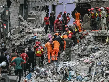 Para petugas penyelamat melakukan operasi pencarian di tengah puing-puing bangunan tempat tinggal yang runtuh di Karachi, Pakistan pada tanggal 5 Juli 2025. (Rizwan TABASSUM/AFP)