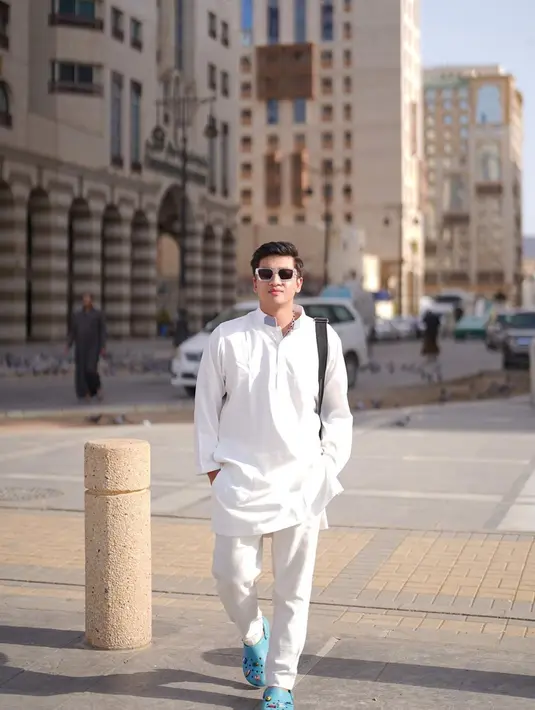 Dengan jepretan dari Rey Mbayang, hasil foto Harris Vriza terlihat indah dengan latar belakang bangunan di Madinah. Gaya OOTD-nya dengan outfit serba putih dipadu kacamata hitam pun mencuri perhatian. Ia pun mendoakan followers-nya agar cepat bisa menyusul ke sana. (Liputan6.com/IG/@harrisvriza)