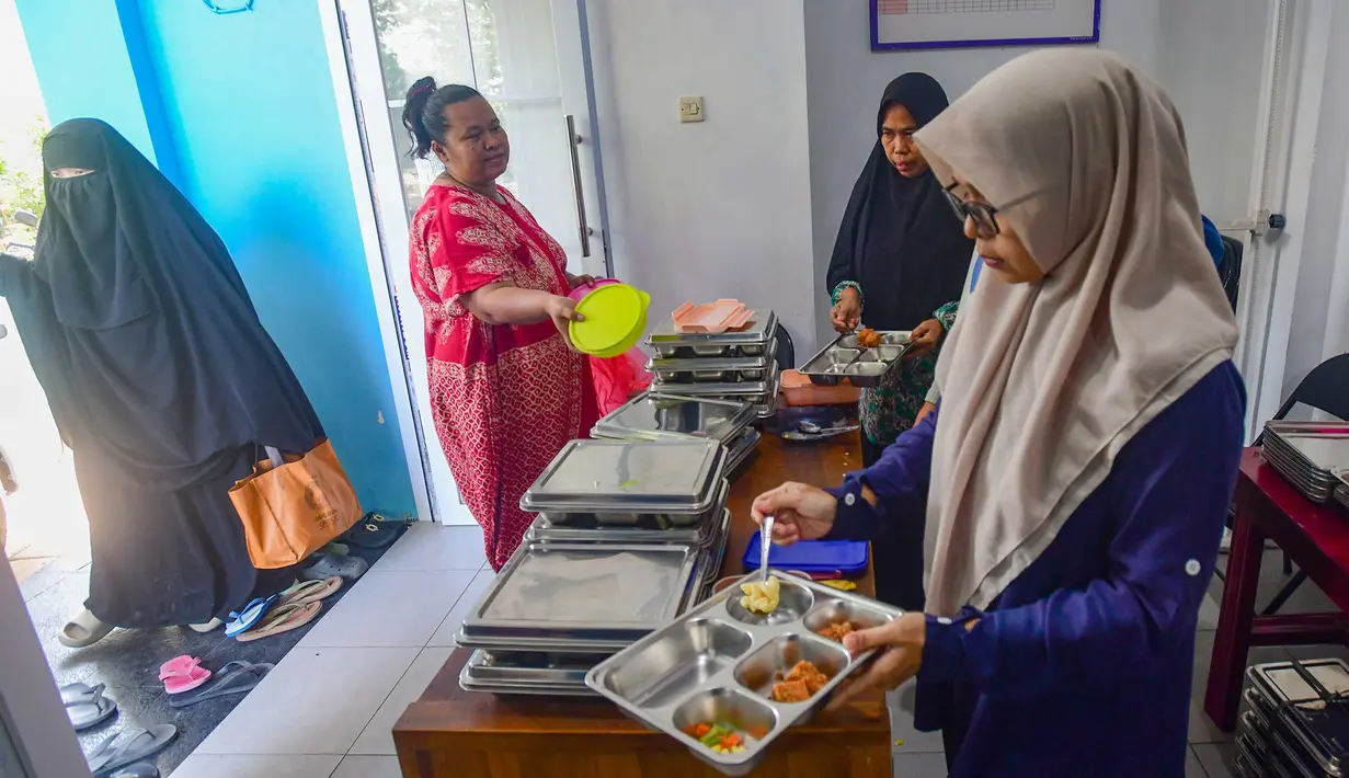 Ibu hamil mengambil makan bergizi gratis (MBG) untuk dikonsumsi di rumah di Posyandu kawasan Limo, Depok, Jawa Barat, Selasa (14/7/2025).