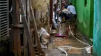 Warga membersihkan jalan di depan rumah mereka yang dipenuhi lumpur setelah banjir melanda lingkungan mereka setelah hujan deras di Jakarta pada Senin 7 Juli 2025. (BAY ISMOYO/AFP)