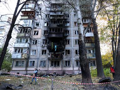 Penduduk setempat berjalan di sekitar gedung bertingkat mereka yang rusak akibat ledakan serangan pesawat tak berawak di Kyiv, pada 30 Oktober 2024. (Anatolii STEPANOV/AFP)