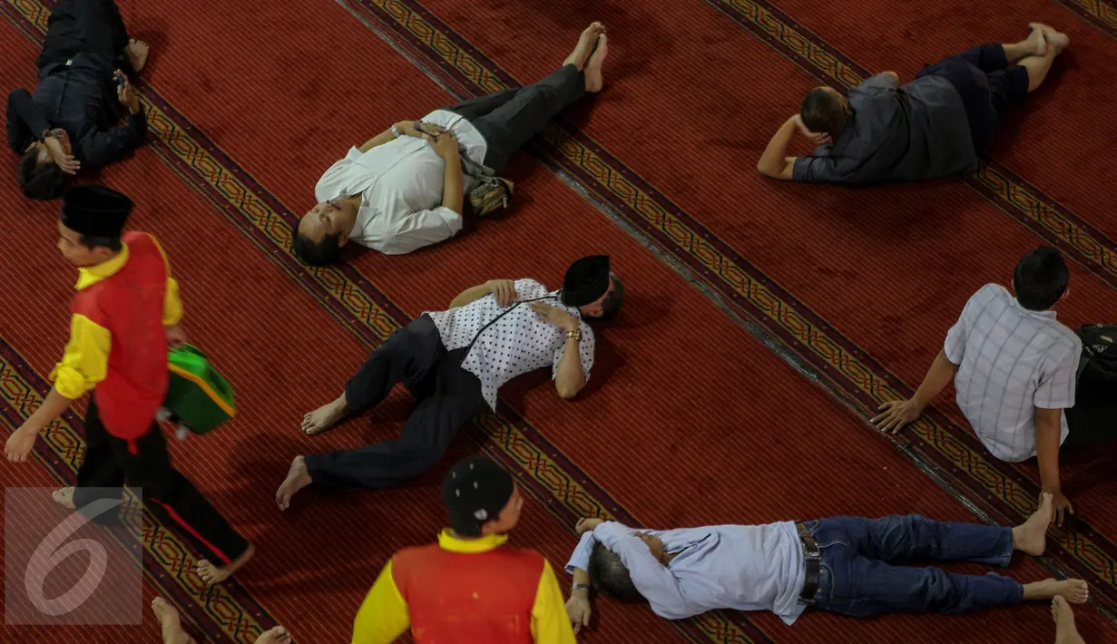Petugas berjalan diantara warga yang tengah tertidur di Masjid Istiqlal, Jakarta, Jumat (19/6/2015). Waktu luang diisi warga dengan berbaring dan beristirahat di masjid sambil menunggu waktu berbuka puasa. (Liputan6.com/Faizal Fanani)