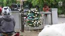Warga berdiri dekat karangan bunga yang bersandar pada tiang lampu yang ditabrak mobil yang ditumpangi Ketua DPR Setya Novanto di Jalan Permata Berlian, Jakarta, Sabtu (18/11). Dalam karangan bunga tersebut tertulis pesan. (Liputan6.com/Angga Yuniar)
