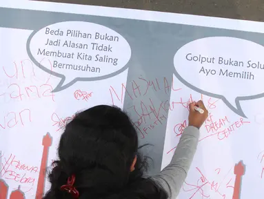 Seorang warga melakukan tanda tangan di bentangan sapanduk panjang di Bundaran HI, Jakarta, Minggu (16/4). Ratusan tanda tangan tersebut di bentuk untuk mendukung pilkada DKI Jakarta yang damai dan tidak golput. (Liputan6.com/Angga Yuniar)
