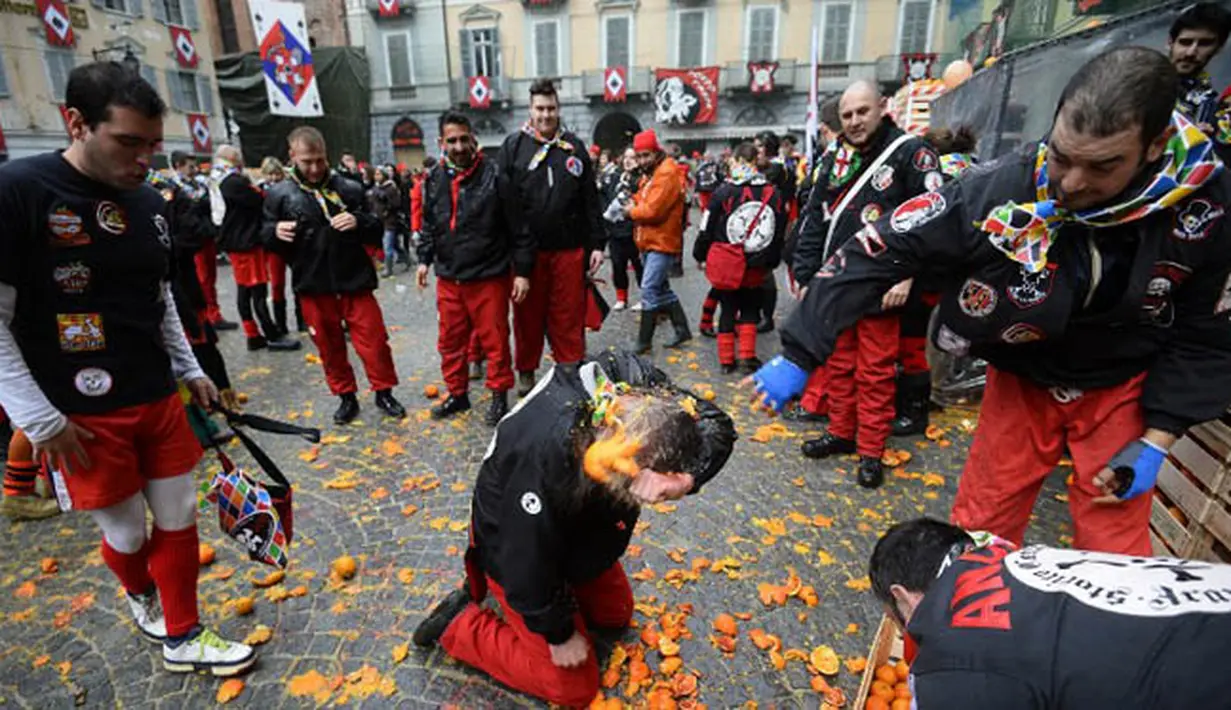 Sekelompok warga turut ambil bagian dalam perang jeruk yang diselenggarakan selama Karnaval Ivrea di Turin, Italia (16/2). (AFP PHOTO/Olivier MORIN)