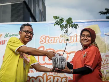 Perwakilan Coolant, Dwianto Arif (kiri) memberikan bibit blimbing kepada Erni Fitratunissa selaku Kepala Bidang Pelestarian & Tata Lingkungan BPLHD kegiatan Coolant Star Fruit di arena Car Free Day, Jakarta, Minggu (25/9). (Liputan6.com/Faizal Fanani)