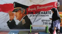 Seorang warga melintasi mural di Kampung Budaya Kawasan Jakarta Barat, Selasa (19/11/2019). Pemprov Jakarta Barat melakukan penataan kawasan pemukiman di beberapa lokasi, salah satunya di Jalan Katalia I Timur. (Liputan6.com/Herman Zakharia)