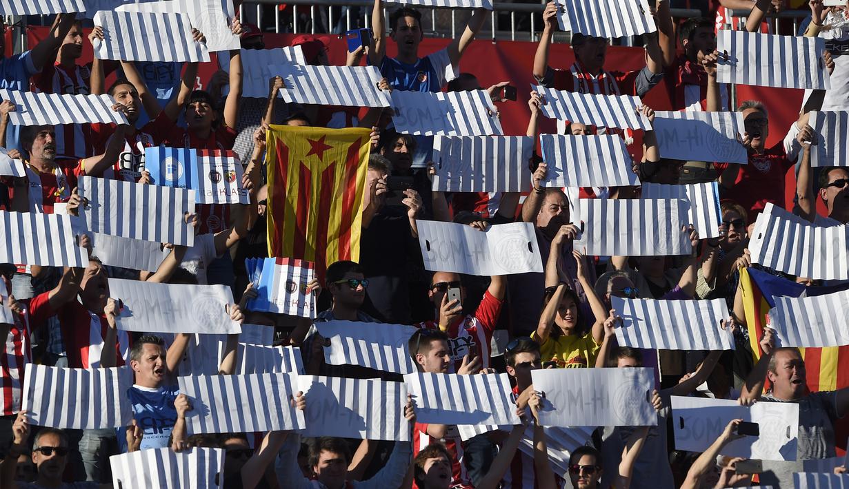 Aksi fans Girona memegang bendera Catalan saat timnya melawan Real Madrid pada lanjutan La Liga Santander di Municipal de Montilivi stadium, Girona , (29/10/2017). Madrid kalah 1-2. (AFP/Josep Lago)