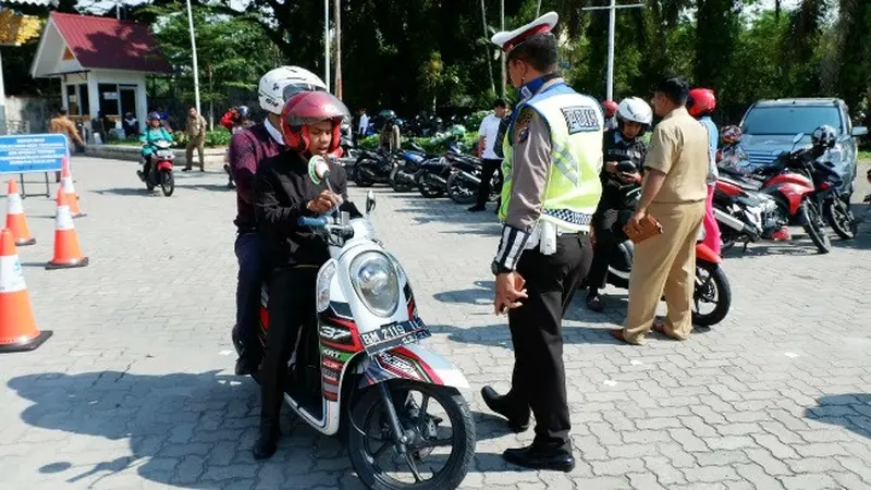 Polisi lalu lintas memberhentikan pengemudi sepeda motor dalam razia pajak kendaraan di Pekanbaru.