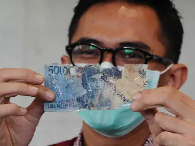 Petugas menunjukkan uang kertas rusak yang ditukarkan warga di Bank Indonesia, Jakarta, Selasa (26/1). BI menerapkan kebijakan untuk mengganti atau menukar uang tidak layak edar dengan uang yang layak edar (Liputan6.com/Angga Yuniar)