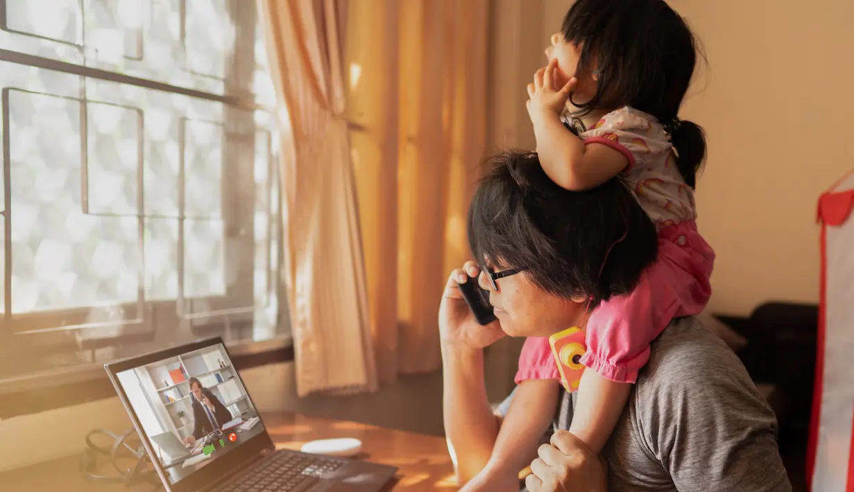 Di sela-sela meeting online dan kesibukan, ayah yang satu ini tetap dengan santai menggendong putrinya tanpa merasa terganggu sedikit pun. (Chatchai.wa/ Shutterstock.com)
