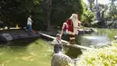 Seorang penjaga kebun binatang membantu seorang pria berpakaian Sinterklas saat dia memberikan hadiah berupa makanan kepada hewan sebagai bagian dari tradisi Natal di Kebun Binatang La Aurora, Kota Guetemala, Selasa (20/12/2022). Makan malam itu akan disebut dengan “Pesta Malam Tahun Baru” yang akan berlangsung pada 31 Desember mulai pukul 18:00 hingga 01:00 keesokan harinya. (Orlando ESTRADA / AFP)
