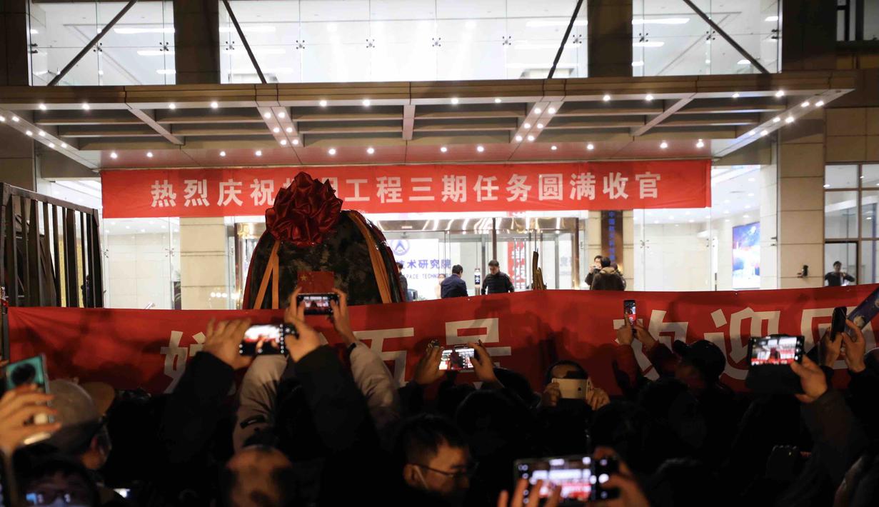 Orang-orang merayakan kedatangan kapsul pembawa pulang (return capsule) wahana antariksa China, Chang'e-5, di Akademi Teknologi Luar Angkasa China di Beijing, ibu kota China (17/12/2020). Sampel Bulan yang dibawanya akan dikirim ke tim peneliti untuk dianalisis serta dipelajari. (Xinhua/Jin Liwang)