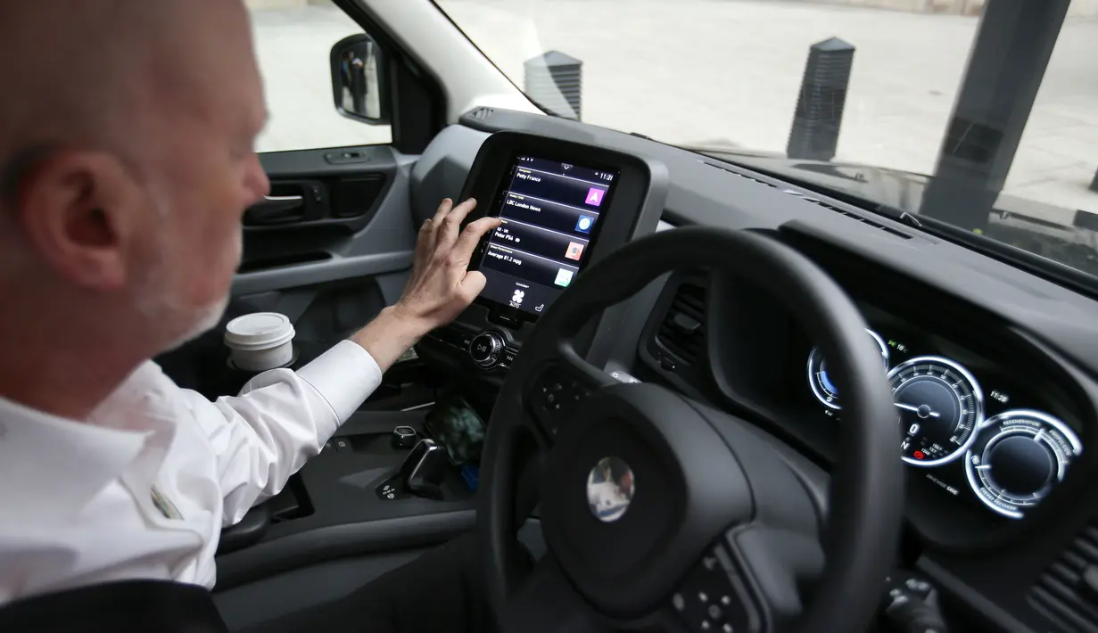 Peter Powell, sopir taksi London, menggunakan layar digital saat mengendarai taksi listrik TX eCity di jalanan London Inggris, Selasa (5/12). Taksi unik warna hitam ini telah berganti mesin elektrik untuk era modern. (AFP PHOTO / Daniel LEAL-OLIVAS)
