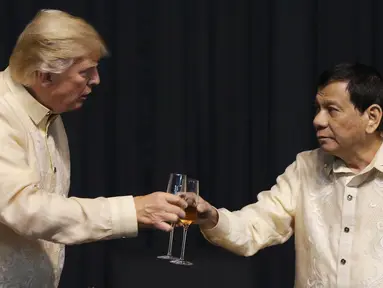 Presiden AS, Donald Trump bersulang dengan Presiden Filipina, Rodrigo Duterte dalam acara makan malam bersama konferensi ASEAN ke-31 di Manila, Minggu (12/11). Trump mengenakan pakaian resmi Filipina yaitu Barong Tagalog. (Athit Perawongmetha/Pool via AP)