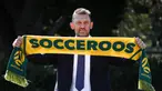 Tony Popovic, pelatih kepala yang baru ditunjuk untuk tim sepak bola nasional Australia, berpose dengan syal setelah konferensi pers di Sydney pada 23 September 2024. (DAVID GRAY/AFP)
