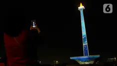 Pengunjung mengambil gambar video mapping dalam Monas Week 2023 di tugu Monumen Nasional (Monas), Jakarta Pusat, Jumat (29/12/2023). (Liputan6.com/Herman Zakharia)