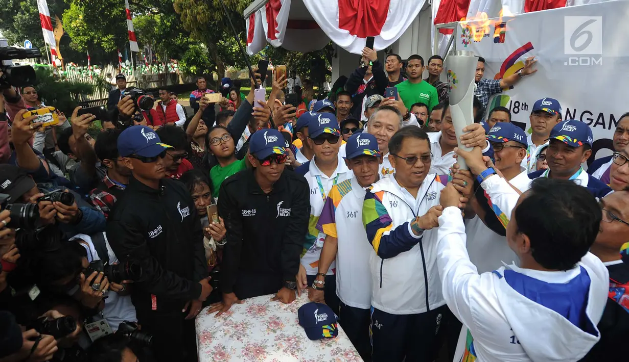 Wali Kota Bogor, Bima Arya Sugiarto menyerahkan obor kepada Menkominfo Rudiantra saat kirab obor Asian Games 2018 di Jawa Barat, Selasa (14/8). Rudiantara menjadi orang pertama pembawa obor dengan berlari sepanjang 500 meter. (Merdeka.com/Arie Basuki)
