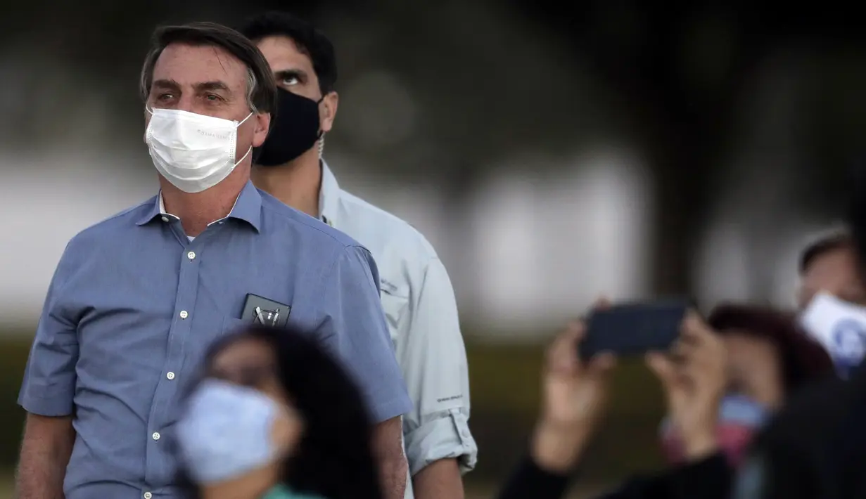 Presiden Brasil Jair Bolsonaro mengenakan masker saat menemui para pendukungnya di luar Istana Alvorada, Brasilia, Brasil, Jumat (24/7/2020). Jair Bolsonaro dinyatakan positif terinfeksi COVID-19 pada 7 Juli lalu. (AP Photo/Eraldo Peres)