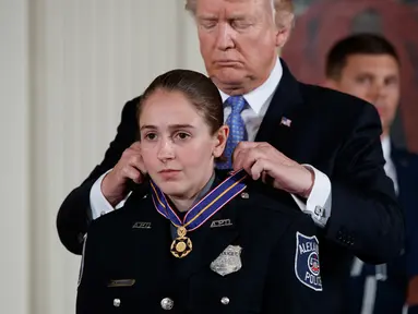 Presiden Donald Trump memberikan Medali Kehormatan kepada Nicole Battaglia dari Departemen Kepolisian Alexandria, Va di Gedung Putih, Washington, (27/7). Lima perwira dapatkan penghargaan atas kasus penembakan di Virginia. (AP Photo/Evan Vucci)