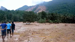 Sejumlah berjalan melintasi salah satu wilayah pemukiman yang terkena longsor di Desa Elangipitiya, Aranayaka, Sri Lanka (19/5). Bencana tanah longsor disebabkan oleh hujan lebat selama berhari-hari di Sri Lanka. (REUTERS/Dinuka Liyanawatte)