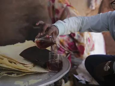 Seorang pria Sudan menuangkan segelas "helo-murr", minuman khas Ramadhan yang terbuat dari jagung kering dan rempah-rempah yang kemudian dicelupkan ke dalam air, di Khartoum, Sudan, pada 22 Maret 2023. (AP Photo/Marwan Ali)