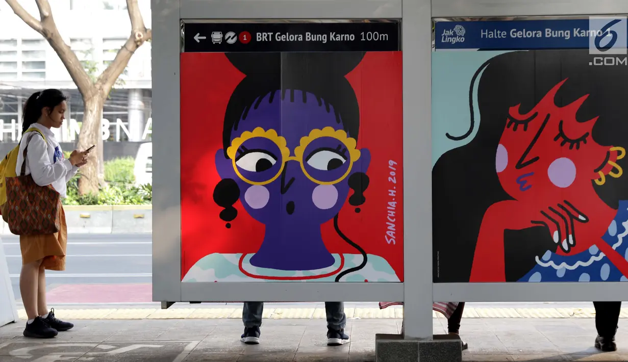 Warga menunggu bus di Halte bus Gelora Bung Karno, Jakarta, Selasa (27/8/2019). Sejumlah karya 10 seniman perempuan Indonesia ditampilkan dalam Jakarta Art Week 2019 menghiasi halte bus dan stasiun MRT di Jalan Jenderal Sudirman. (Liputan6.com/Helmi Fithriansyah)