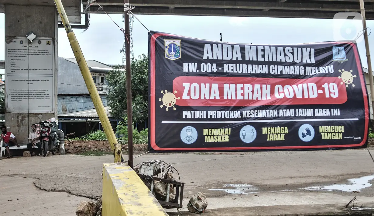 Aktivitas warga di dekat spanduk peringatan Zona Merah di RW 004, Kelurahan Cipinang Melayu, Kecamatan Makassar Jakarta, Rabu (27/1/2021). Pemprov DKI Jakarta mencatat sebanyak 54 rukun warga (RW) menjadi zona merah Covid-19 per 21 Januari 2021. (merdeka.com/Iqbal S Nugroho)