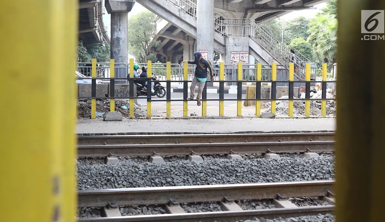 Pejalan kaki melewati pagar perlintasan kereta api di kawasan Tanjung Barat, Jakarta, Senin (7/1). Sejumlah pejalan kaki tetap memilih untuk melompati pagar pembatas dari pada menggunakan fasilitas JPO. (Liputan6.com/Immanuel Antonius)