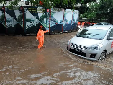 Petugas PPSU Kel Kuningan Barat mengatur lalu lintas di putaran kolong fly over Kapten Tendean, Jakarta, Selasa (9/2/2016). Hujan deras yang mengguyur Jakarta mengakibatkan putaran ini tergenang air. (Liputan6.com/Helmi Fithriansyah)